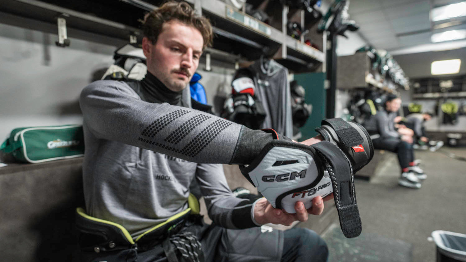 Person adjusting a hockey glove in a locker room setting